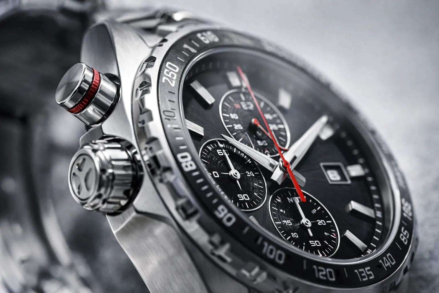 Kronografipainikkeet, kruunu ja kellotaulun asettelu, joka havainnollistaa toiminnallisia ohjaimia ja luettavuutta korkeanopeusajon olosuhteissa